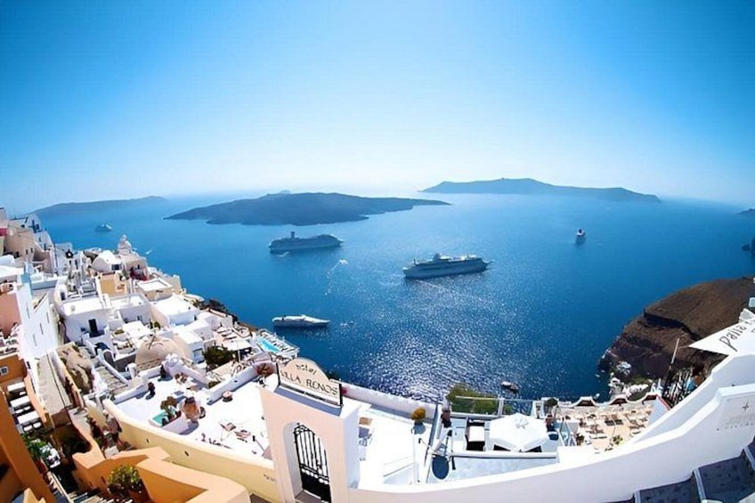 A coastal town with white buildings, a clear blue sea, and several boats. 2