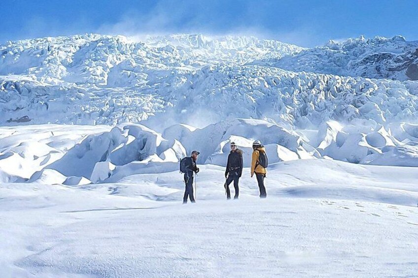 Trois personnes font de la randonnée sur une montagne enneigée, sous un ciel dégagé. 3