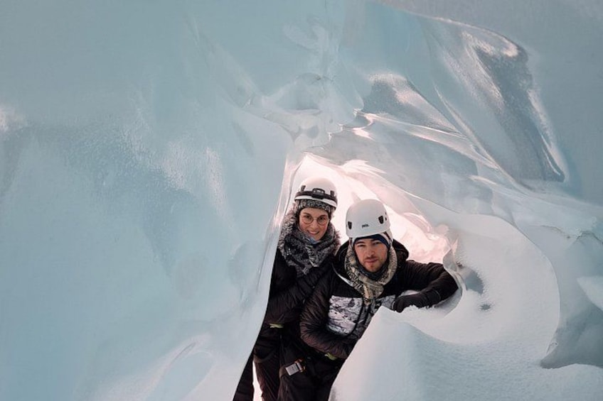 Two people in a snowy cave with ice walls. 1