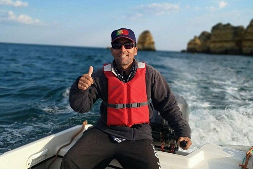 A person on a boat wearing a life jacket and a cap, with a thumbs-up gesture. 2