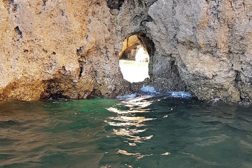 A rocky cave entrance with clear water flowing through it. 2