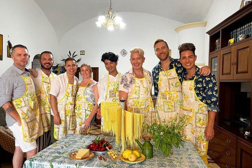 Un grupo de personas en una cocina con pasta, limones y una planta sobre la mesa. 3
