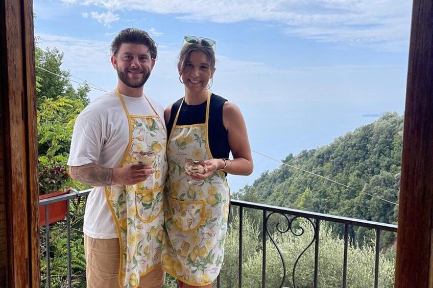 Dos personas en un balcón con una vista panorámica de una ladera boscosa y una masa de agua. 4