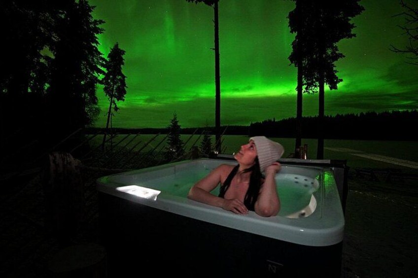 A person relaxing in a hot tub with a view of the northern lights. 2
