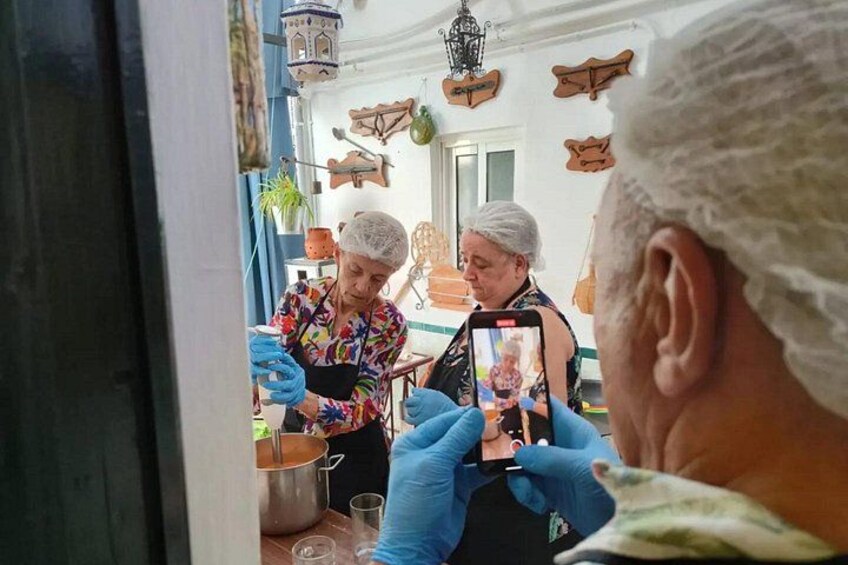 Eine Person fotografiert zwei Personen in einer Küche. 2