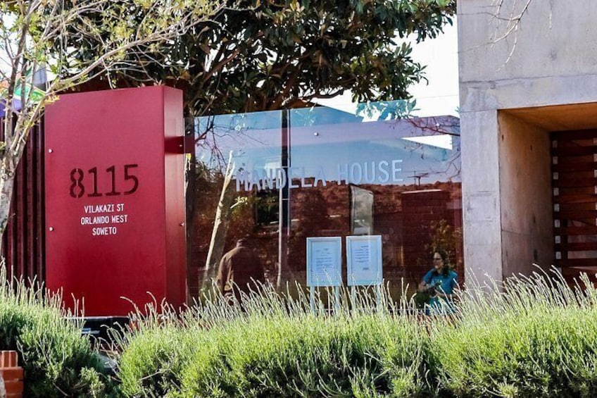 A red mailbox with the number 8115, a building with a glass facade, and a person sitting on a bench. 3