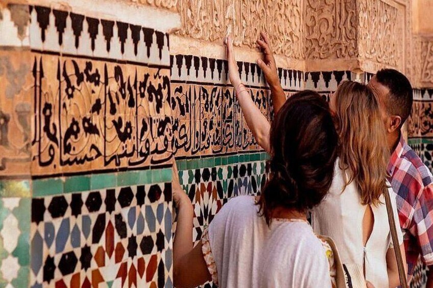 People examining intricate tile work with Arabic calligraphy. 3