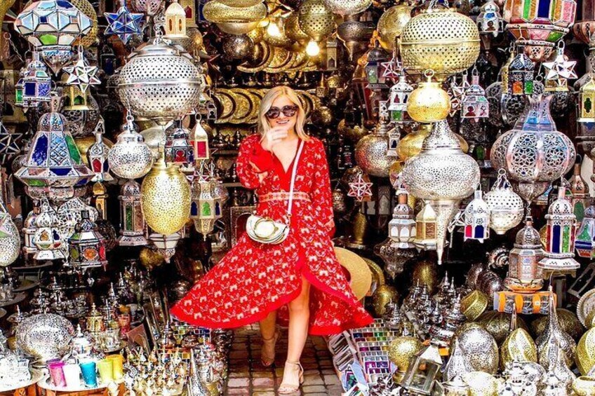 A person in a red dress surrounded by ornate metal lanterns and decorative items. 2