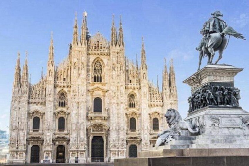 A grand cathedral with intricate Gothic architecture, a prominent statue of a historical figure on horseback, and a lion sculpture in the foreground. 1