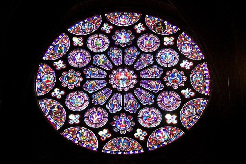 A circular stained glass window with intricate floral and geometric patterns. 1