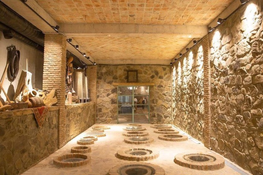 Una habitación de paredes de piedra con diseños circulares en el suelo, una chimenea y diversas herramientas en la pared. 5