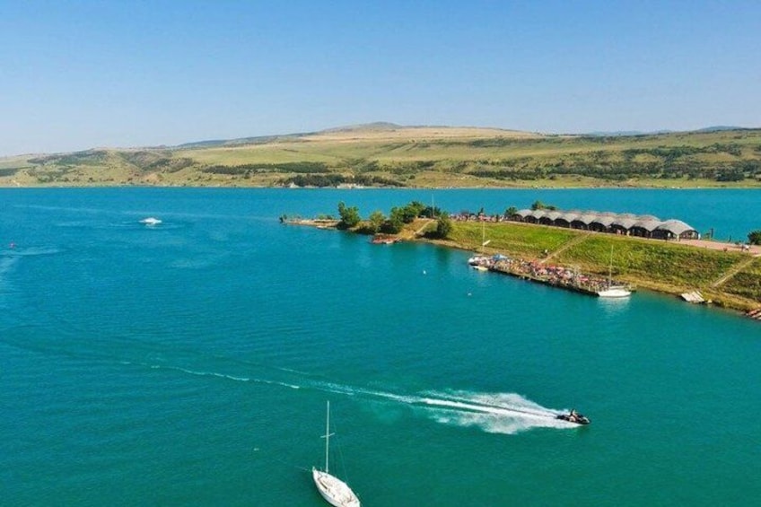 Un lago con un bote, un jet ski y un muelle con edificios. 4