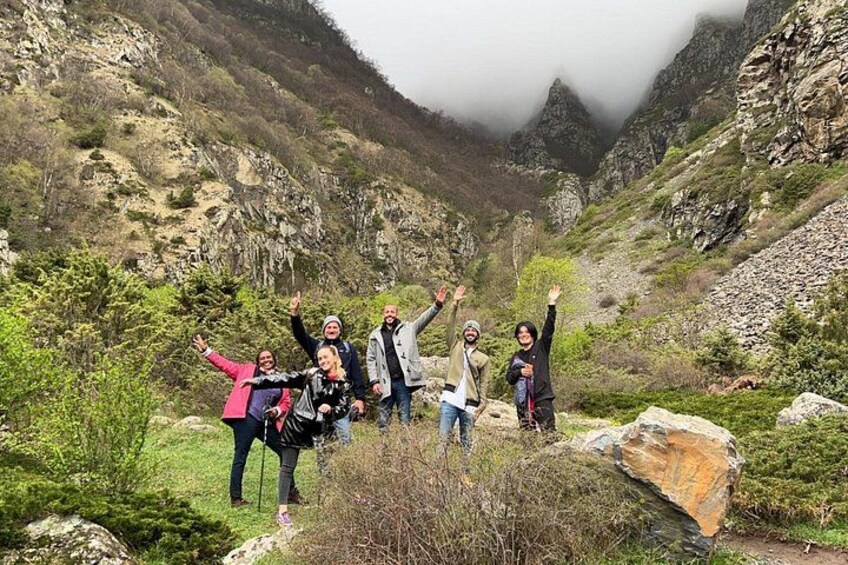 A group of people hiking in a mountainous area with rocky terrain and greenery. 3
