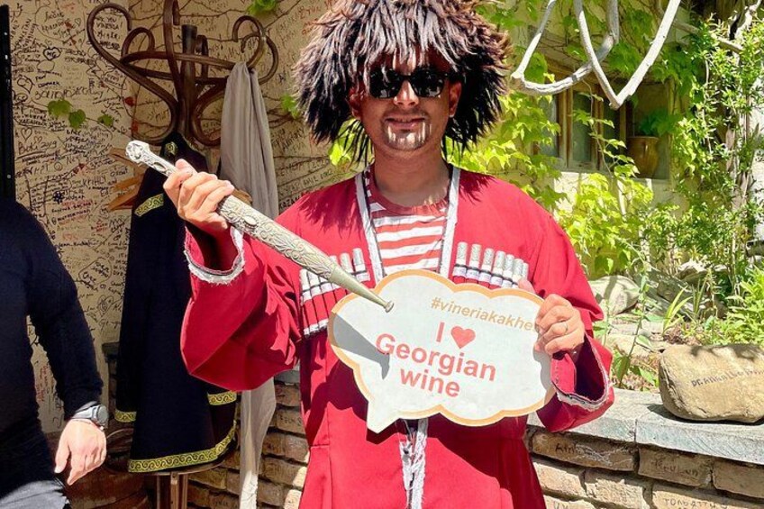 Una persona con una chaqueta roja sosteniendo un cartel que dice 'I love Georgian wine'. 5