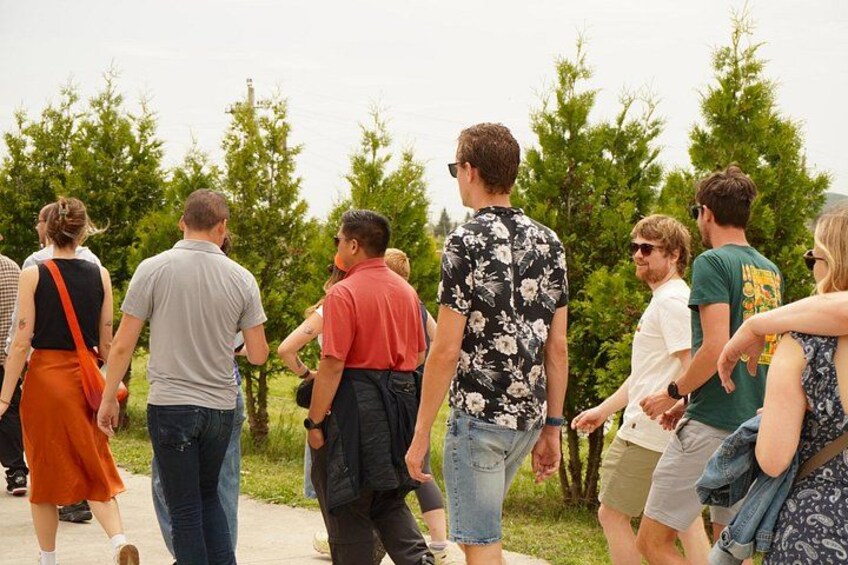 A group of people walking outdoors, surrounded by trees and greenery. 2
