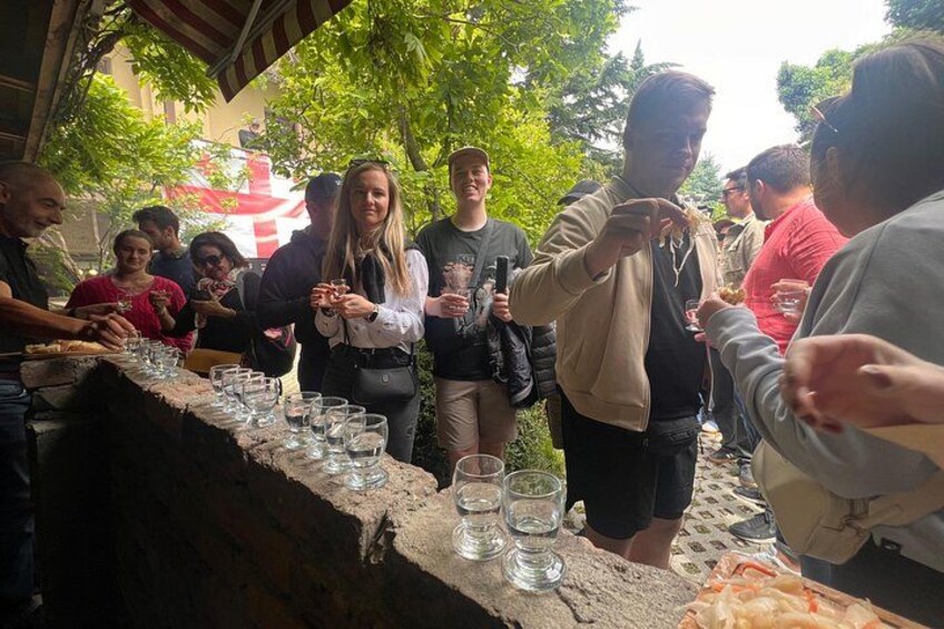 A group of people standing around a table with glasses and a plate of food. 2