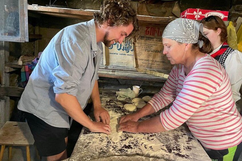 Dos personas trabajando con masa sobre una superficie cubierta de harina en una cocina rústica. 2