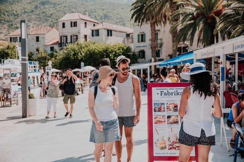 A crowded street with people walking, a signboard, and buildings in the background. 3