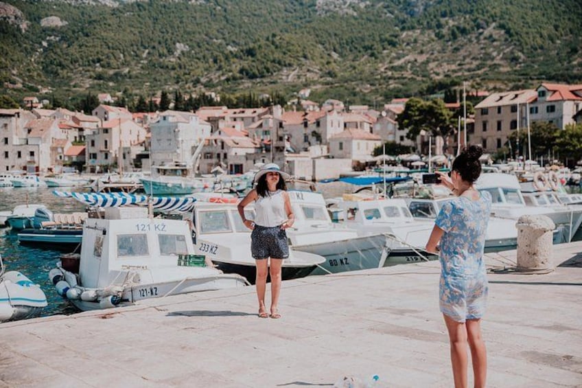 Un port de plaisance sur la côte, avec des bateaux amarrés, une femme qui prend une photo et un homme qui se tient à proximité. 3