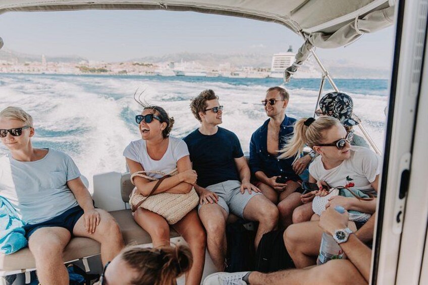 A group of people on a boat with a coastal landscape in the background. 3