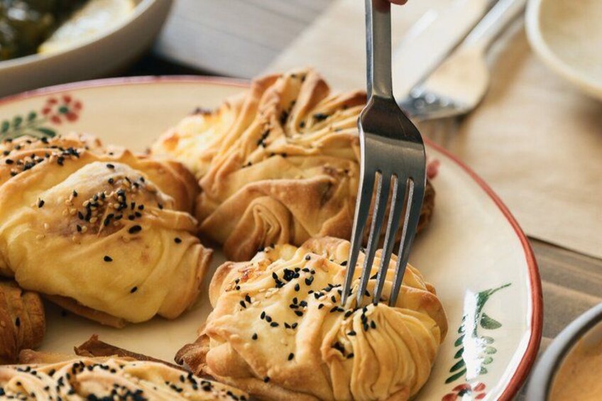 Een bord met gebakjes met sesamzaadjes, een vork en een bord met bloemendecoratie. 4