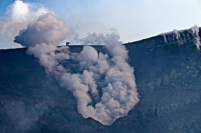 A volcanic crater with smoke rising from it. 1