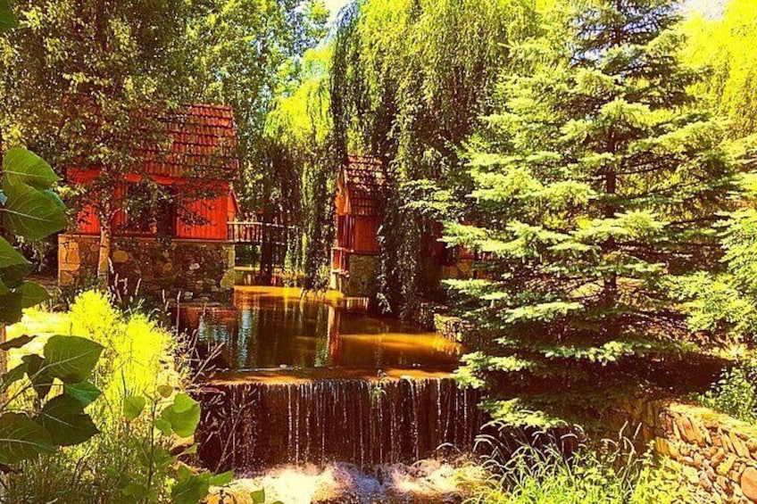 A waterfall, red-roofed buildings, and dense green trees. 1
