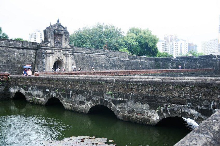 Eine Stebrücke über Wasser mit einem Tochturm und einer Stadtkulisse im Hintergrund. 5