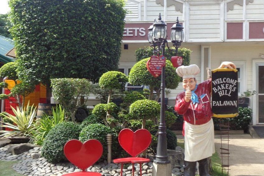 A chef statue, heart-shaped decorations, and a sign welcoming visitors to Bakers Hill Palawan. 5