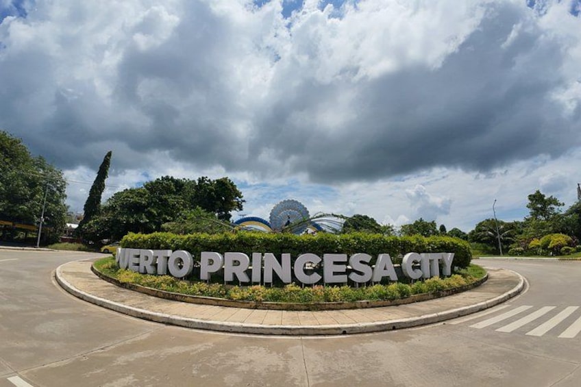 A sign for 'Verto Princesa City' with a roundabout and greenery in the background. 2