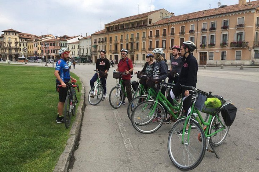 En gruppe cyklister på en gade i byen med bygninger i baggrunden. 2