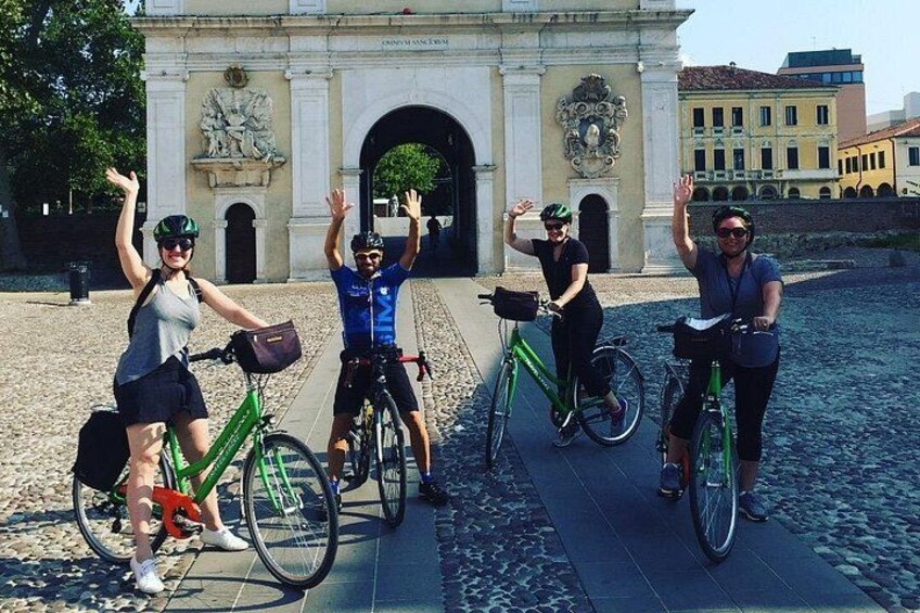 Un grupo de personas en bicicleta frente a un edificio histórico con un arco. 1