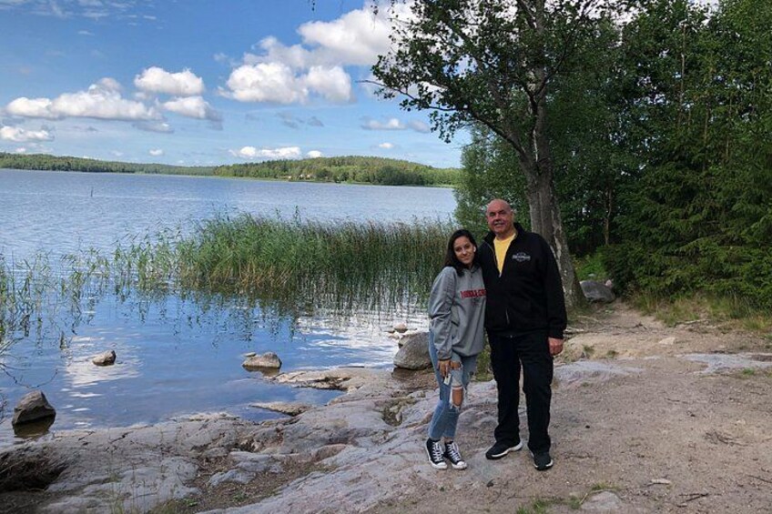 A lake with rocks and trees, a clear sky, and a person standing on the shore. 2