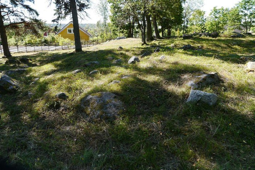A grassy area with scattered rocks, trees, and a yellow building in the background. 2