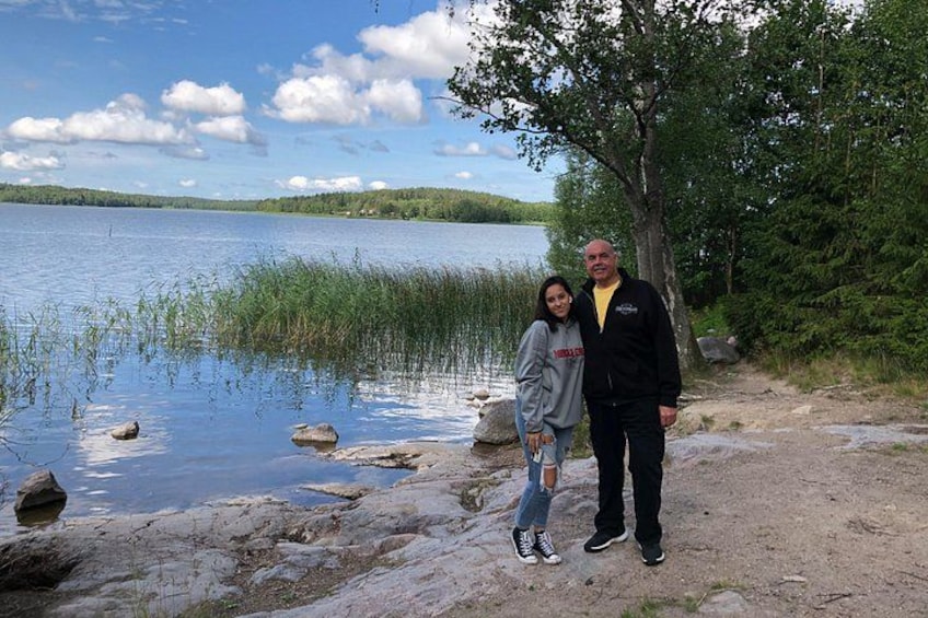 En sjö med stenar och träd, en klar himmel och en person som står på stranden. 2