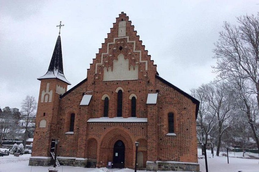 Una chiesa in mattoni con un campanile a guglia e un tetto imbiancato dalla neve. 4