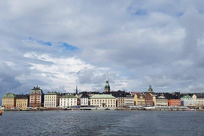 A waterfront cityscape with historic buildings and a prominent church spire. 2