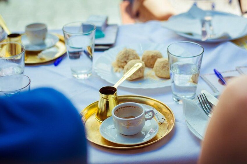 A table with a cup of coffee, glasses of water, and plates of food. 2