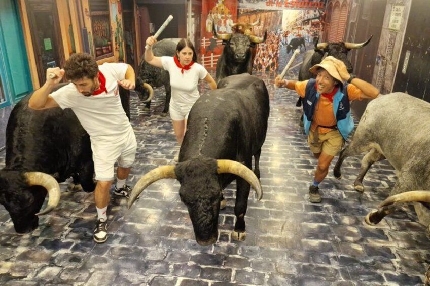 A museum exhibit with life-sized bull statues and a person in a white shirt and shorts. 5