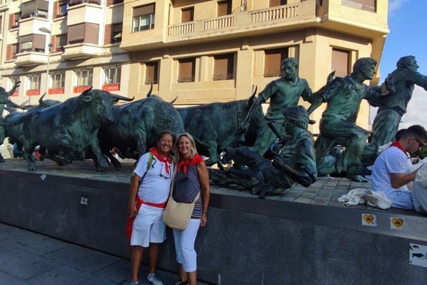 A group of people posing in front of a sculpture of bulls and a building with balconies. 3