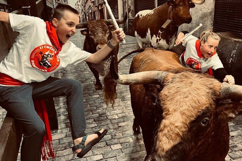 A person riding a bull in a narrow street. 2