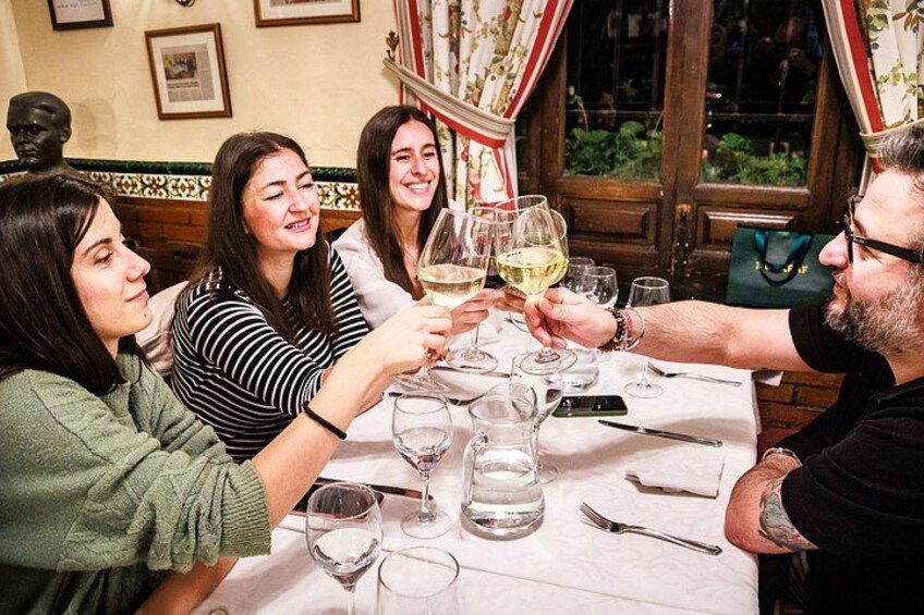 A group of people toasting with wine glasses at a table in a restaurant. 2