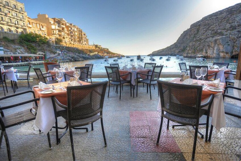 En kystrestaurant med borde dækket til spisning, med udsigt over havet og en klippefyldt kystlinje. 5