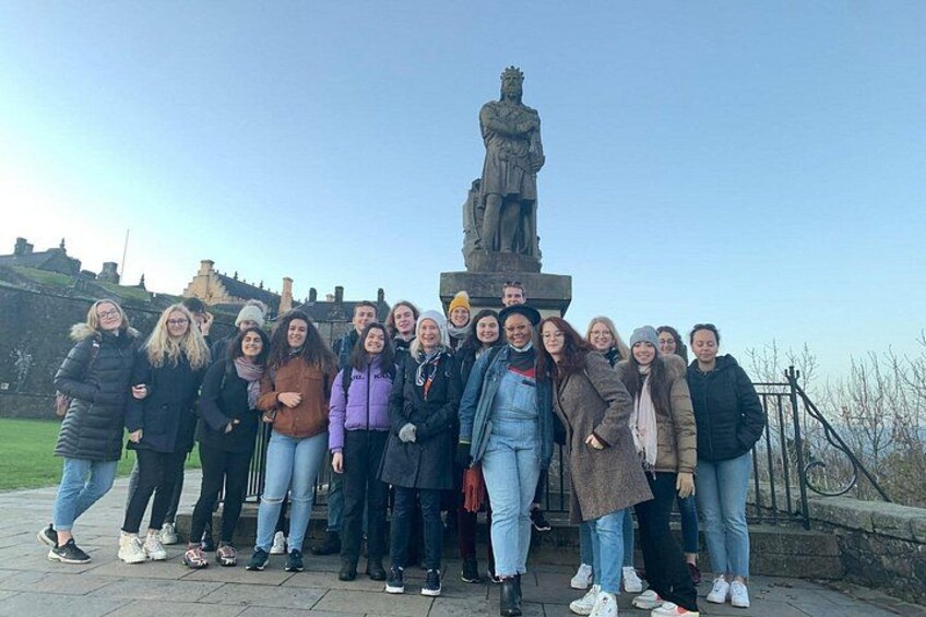Een groep mensen poseert voor een standbeeld in een park. 5