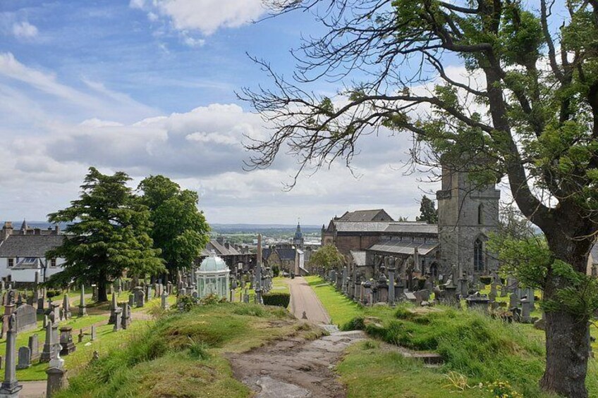 A cemetery with headstones, a church, and a large tree. 4