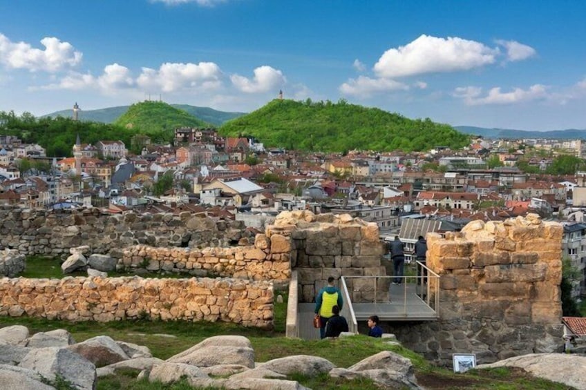 Ancient stone ruins, a town in the background, and a clear sky. 4