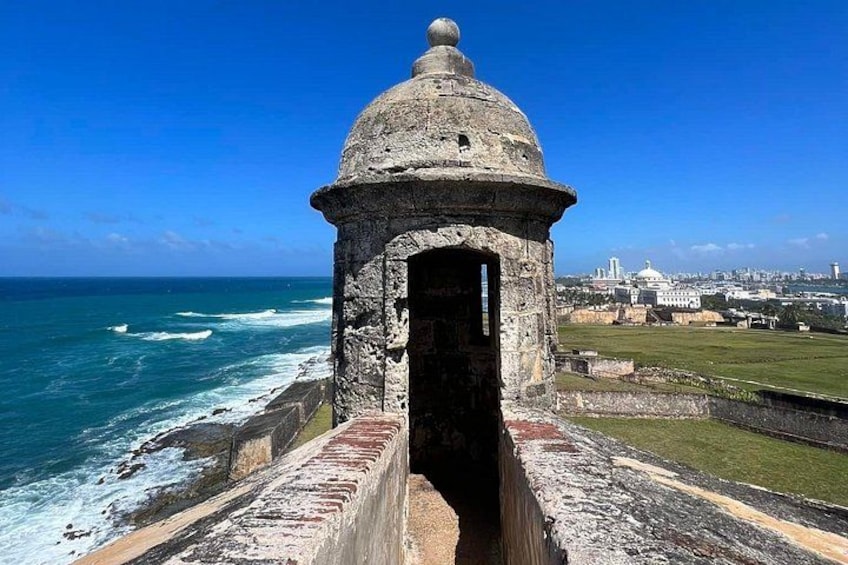 A coastal fort with a dome structure, overlooking the ocean and a cityscape in the background. 3