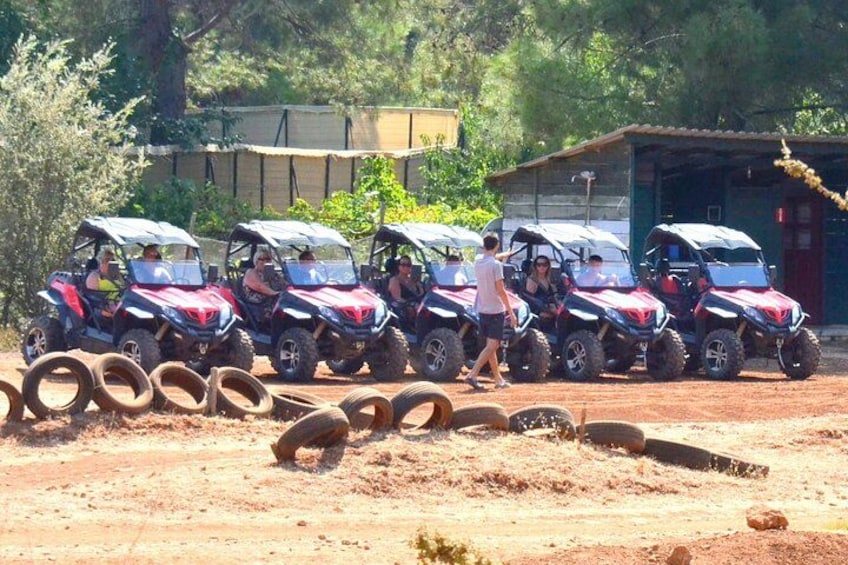 A row of ATVs parked on a dirt road with spare tires in the foreground. 3