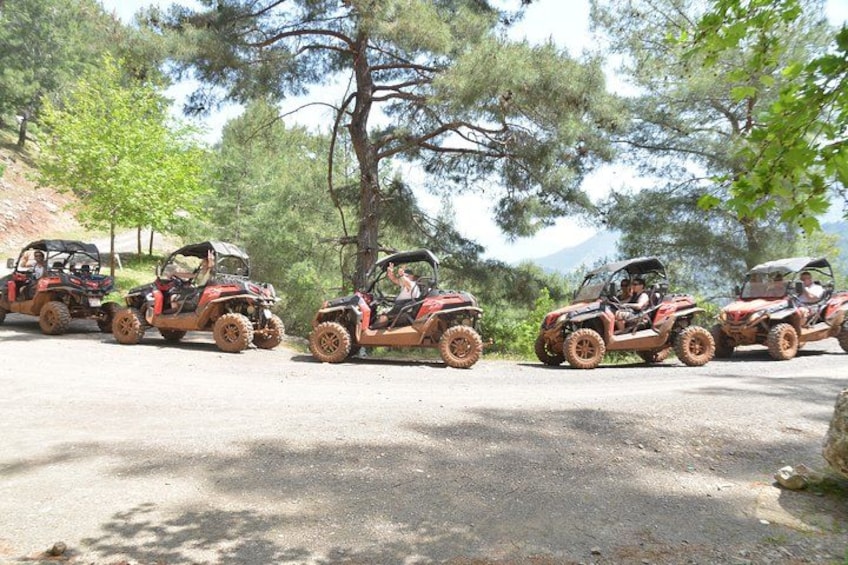 Four off-road vehicles on a dirt road surrounded by trees. 2
