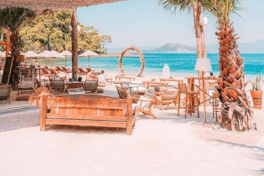 A beachside lounge with wooden furniture and palm trees. 5